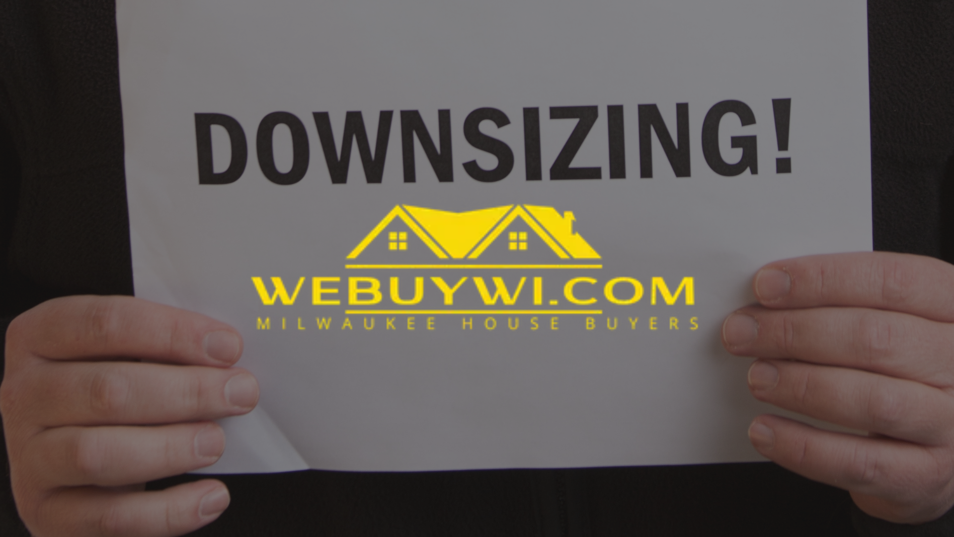 Hands holding a sign that reads 