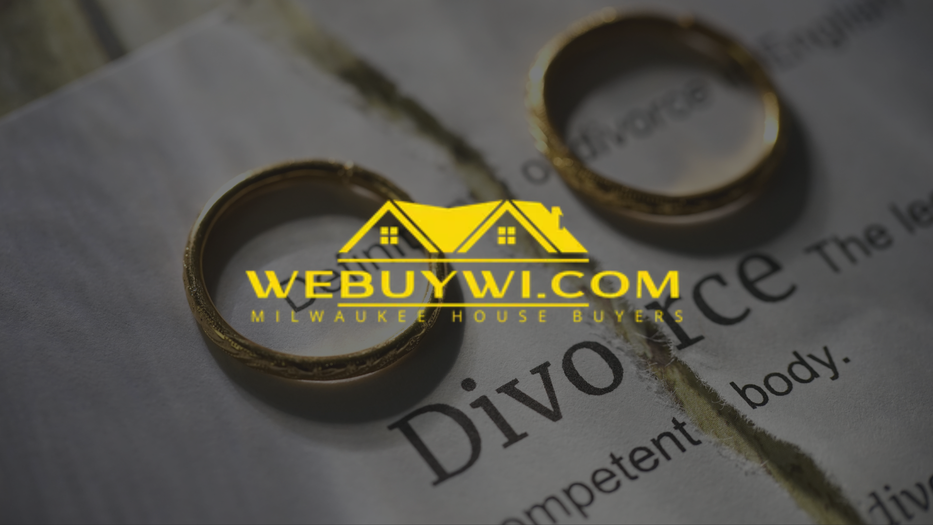 Two wedding rings are sitting on top of a piece of paper that says divorce.