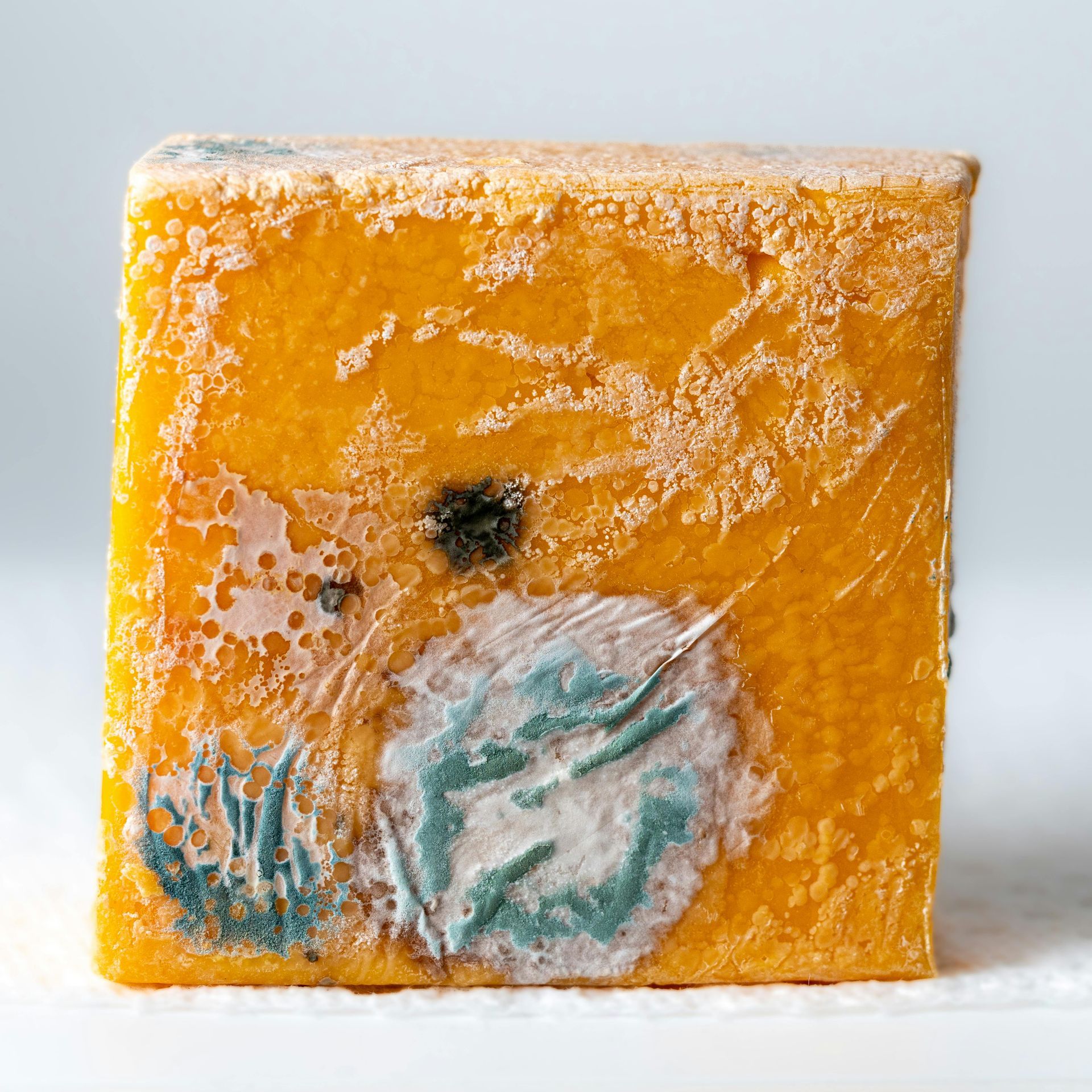 Orange square soap bar with frosted surface and blue-green floral design on the front