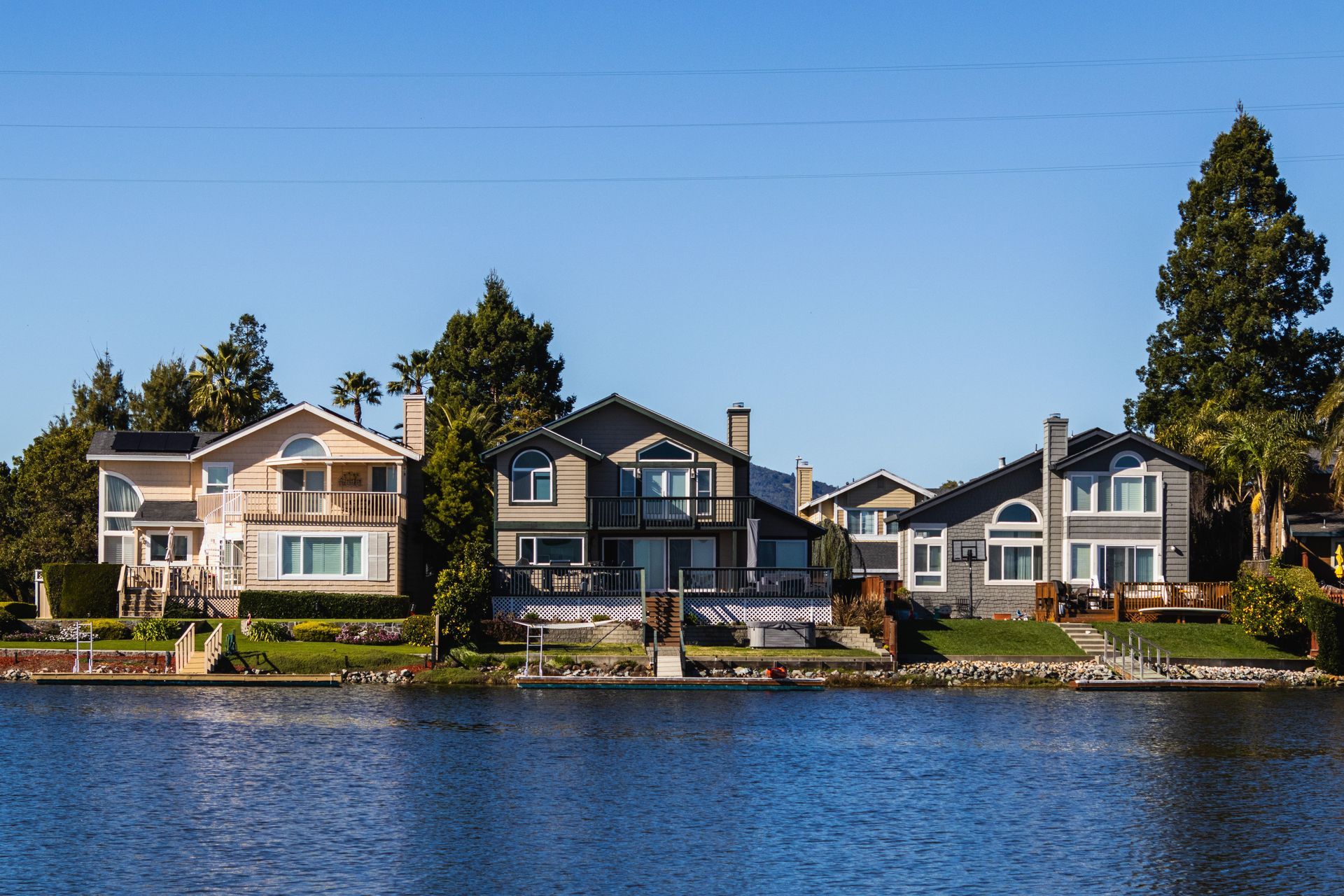Waterfront houses with docks along a calm blue shoreline under a clear sky