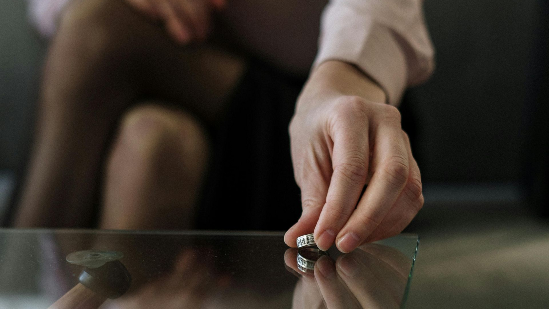 Hand placing a ring on a glass table.