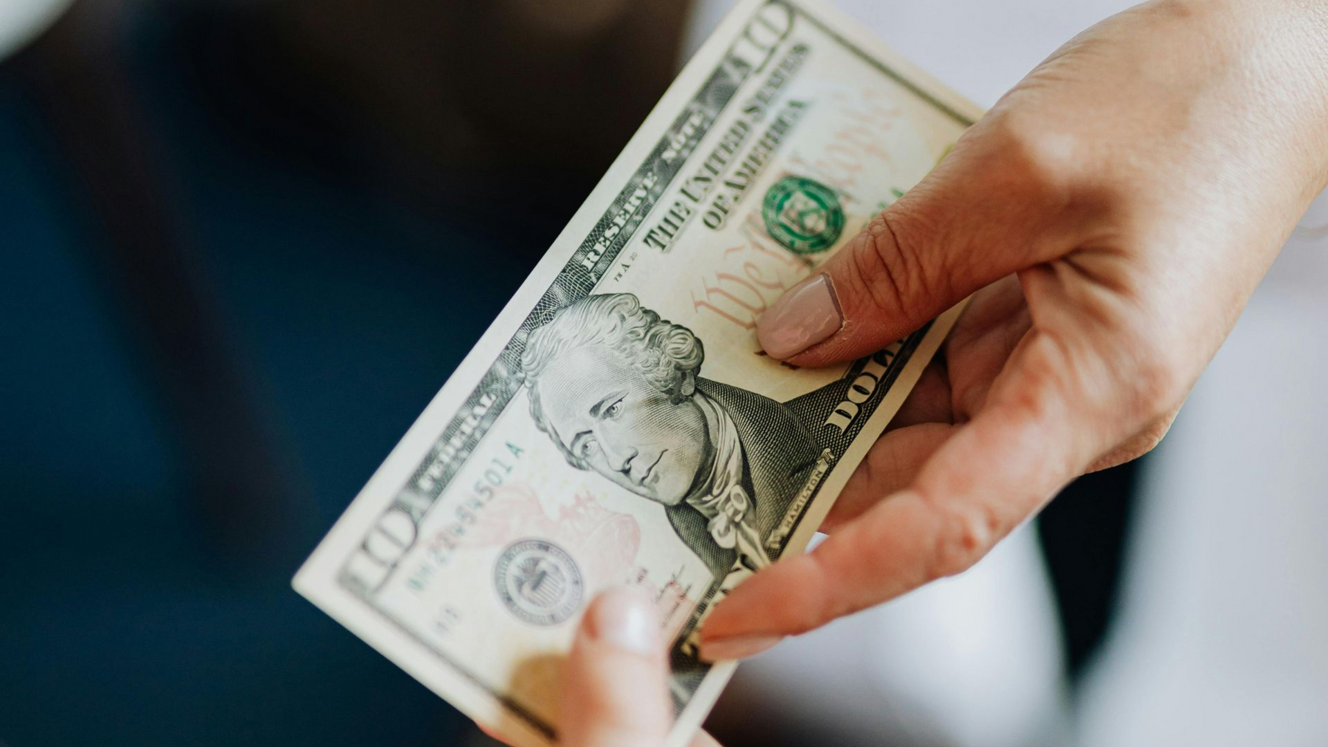 A hand fanned out several American one-hundred-dollar bills.