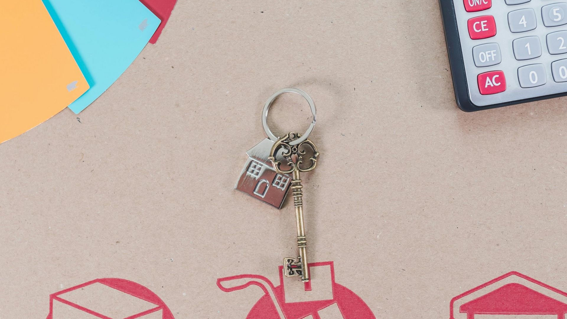 A house-shaped keychain with a vintage key, a partial calculator, and color swatches on a cardboard background.
