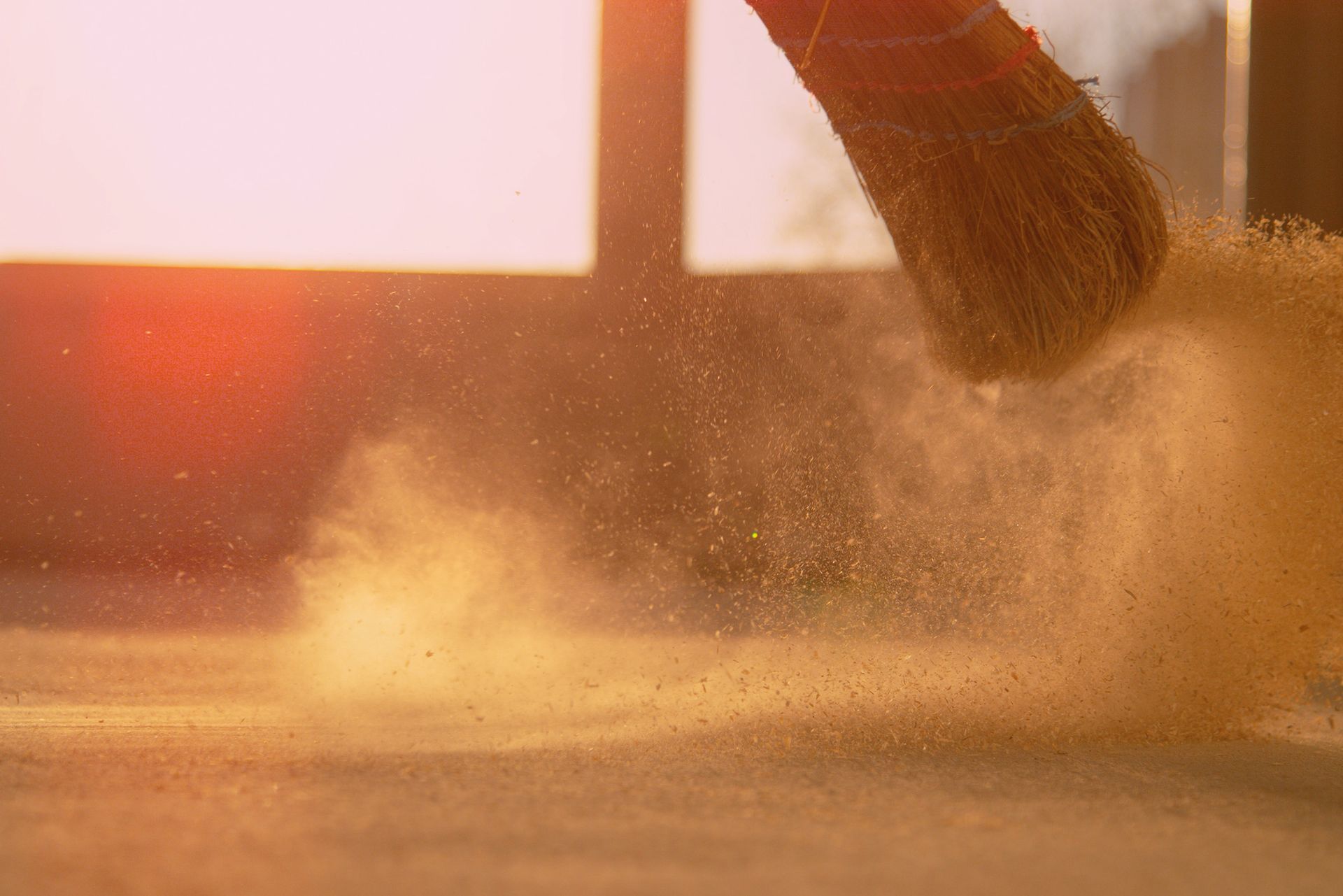 A person is dusting the floor with a brush.