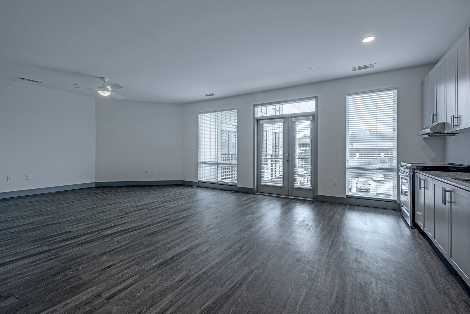 An empty living room with hardwood floors and a kitchen.