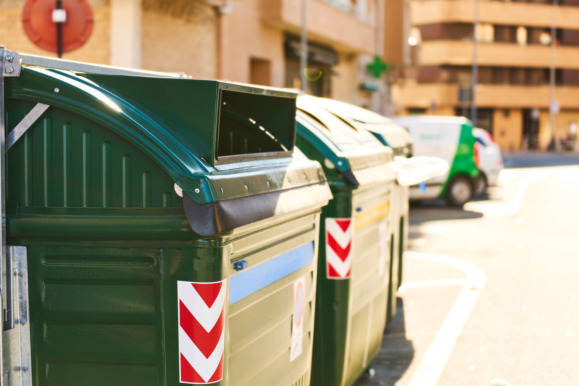 A row of green garbage cans with red and white arrows on them.