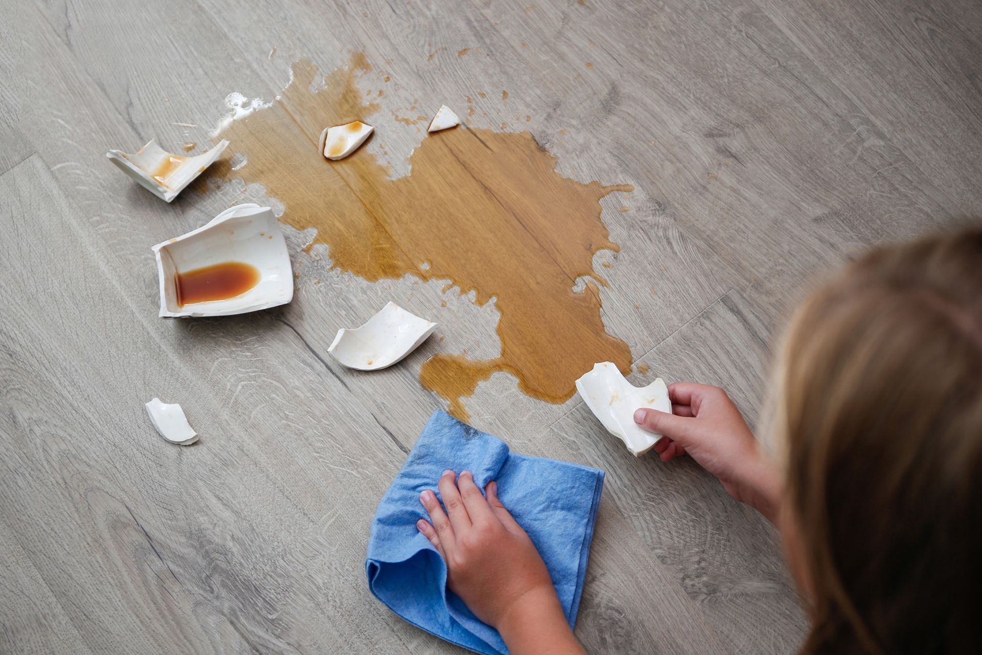 A child is cleaning a spilled cup on the floor.