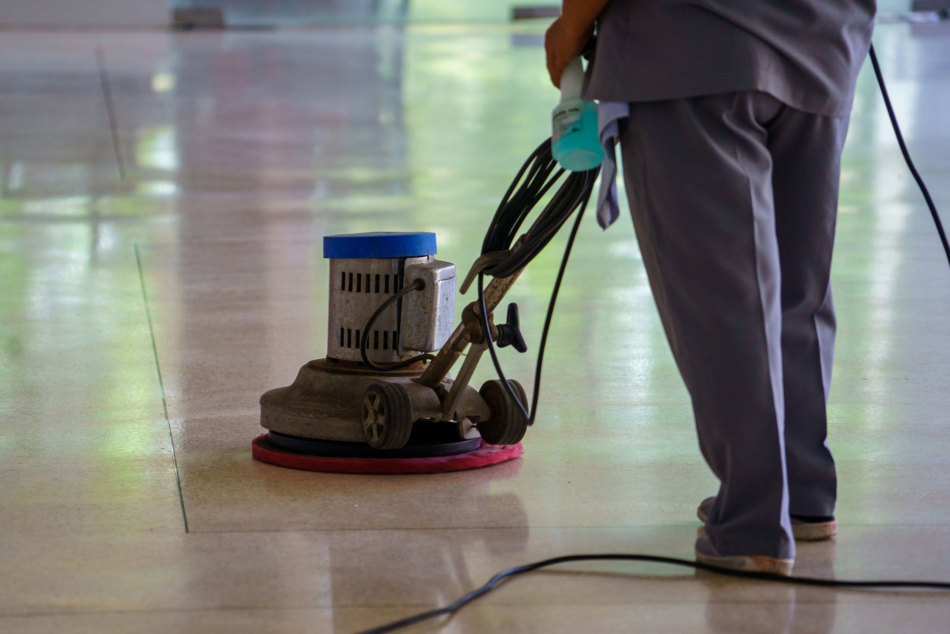 A person is using a machine to clean a tiled floor.