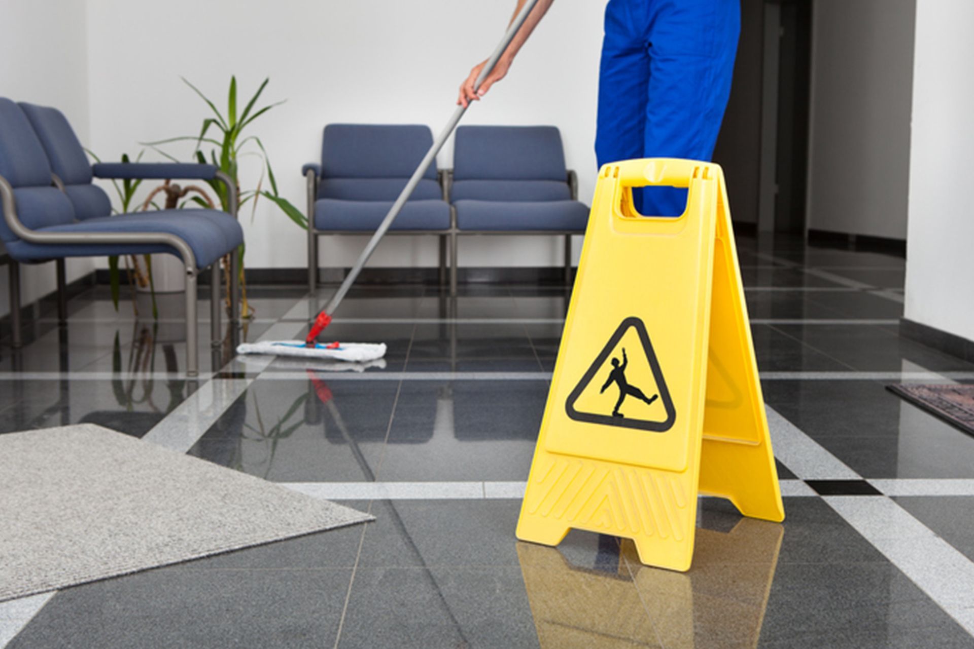 A man is mopping the floor next to a yellow caution sign.