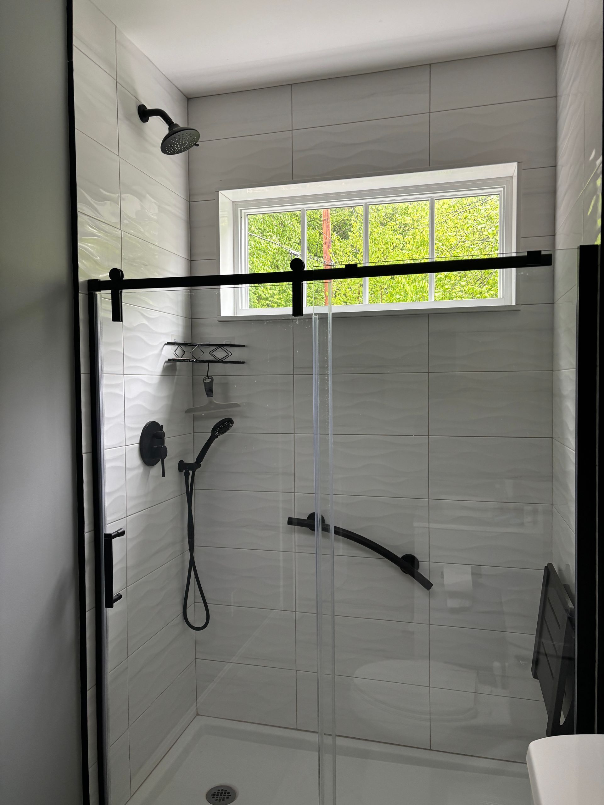 A bathroom with a sliding glass shower door and a window.