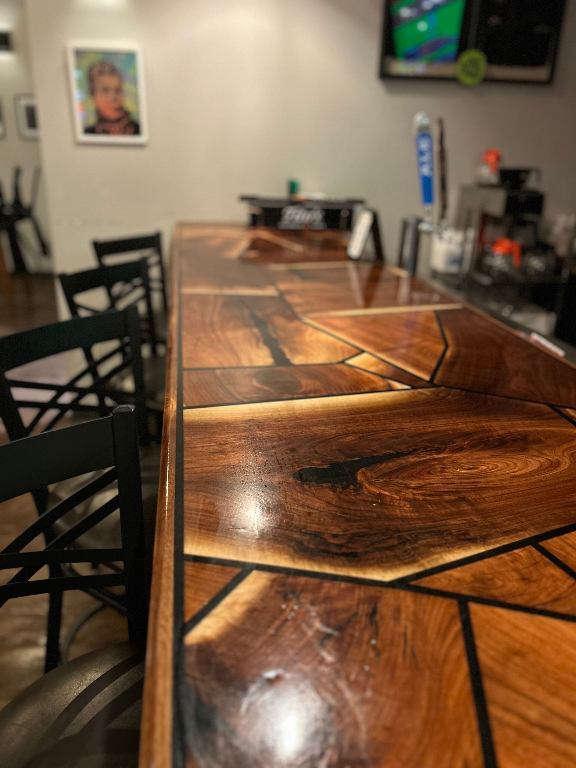 A bar made of wood and resin in a restaurant with chairs.