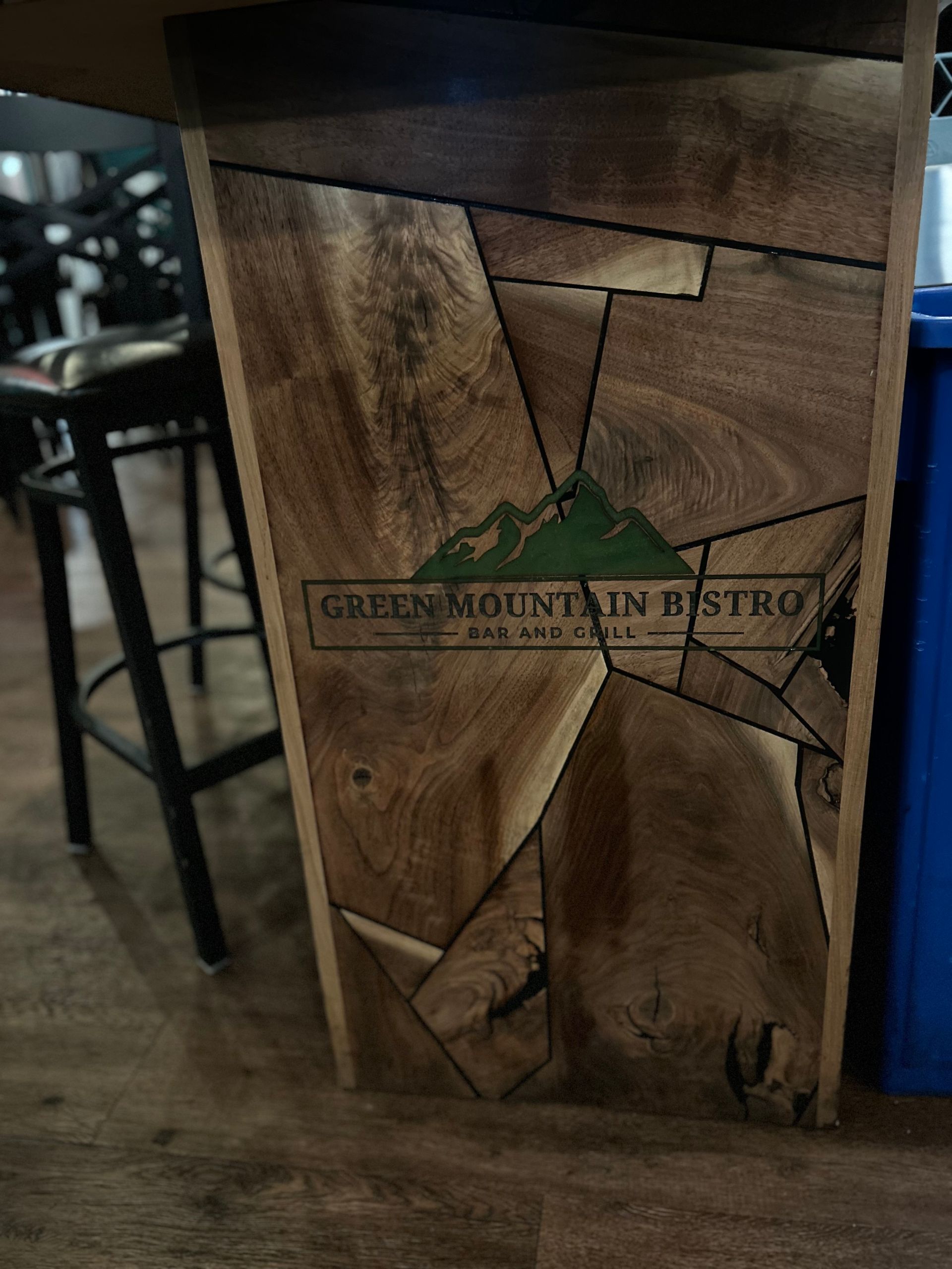 A wooden table with a green mountain bistro logo on it.