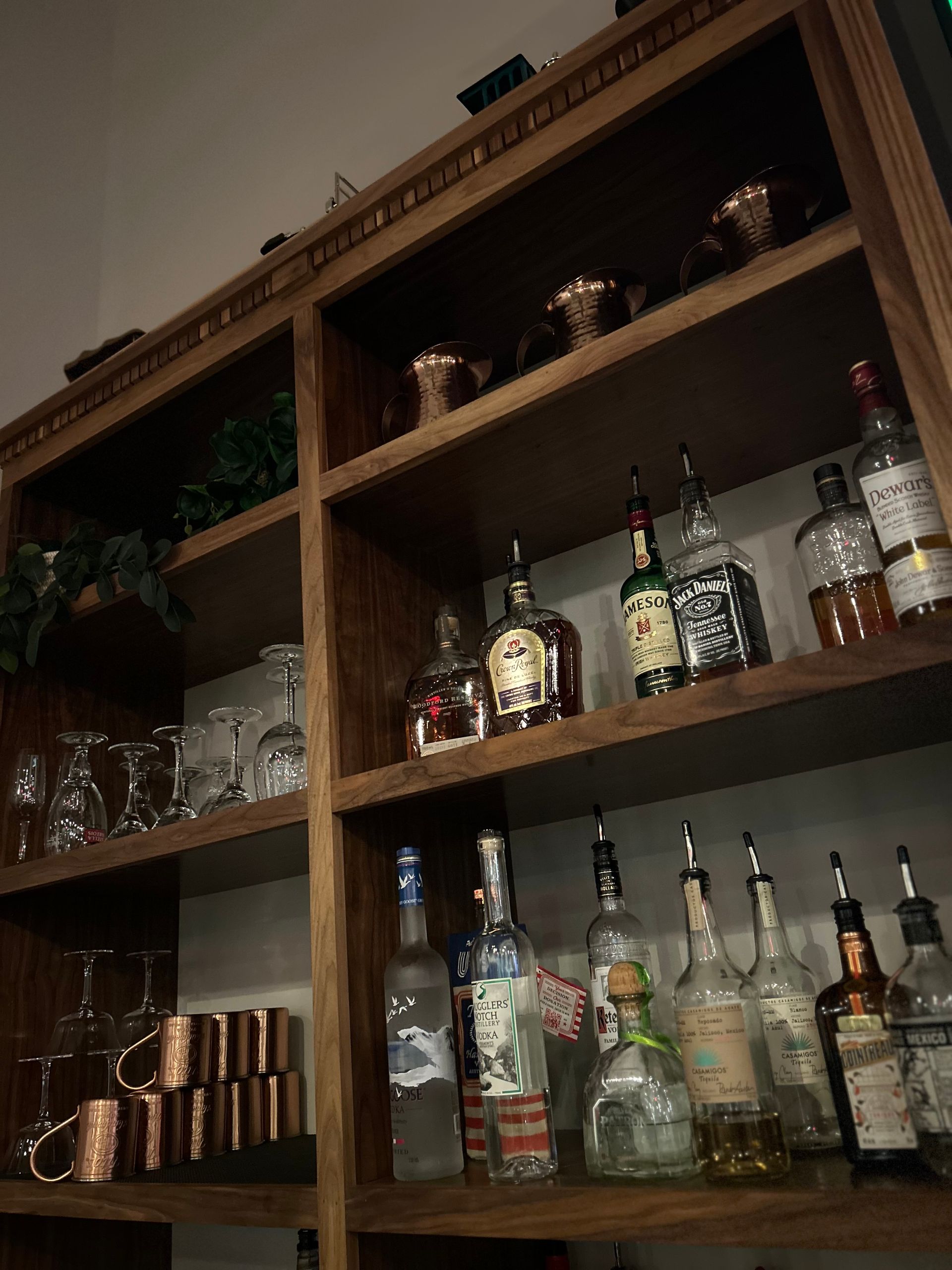 A shelf filled with bottles of liquor and glasses