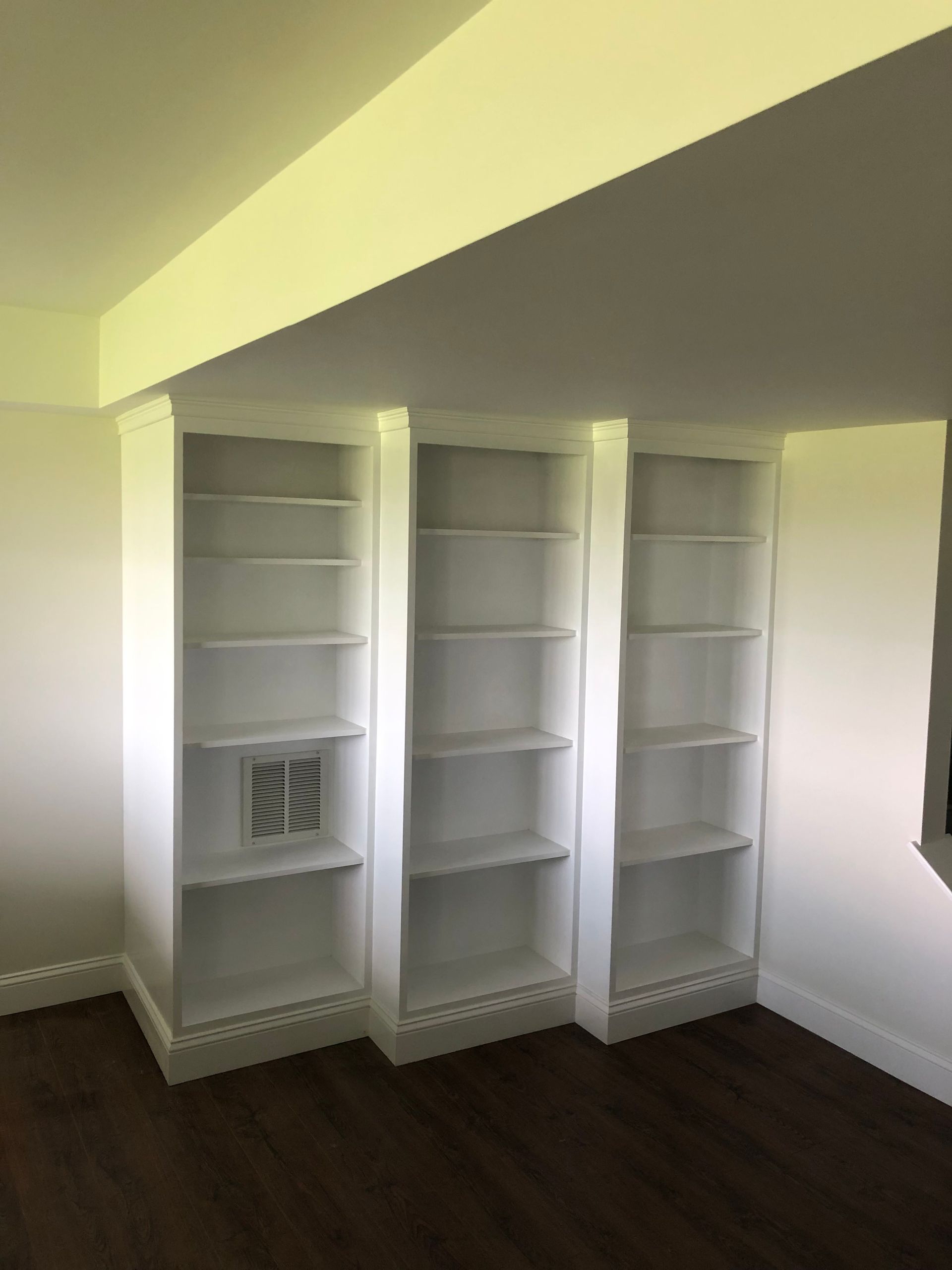 A room with three white shelves and a picture on one of them.