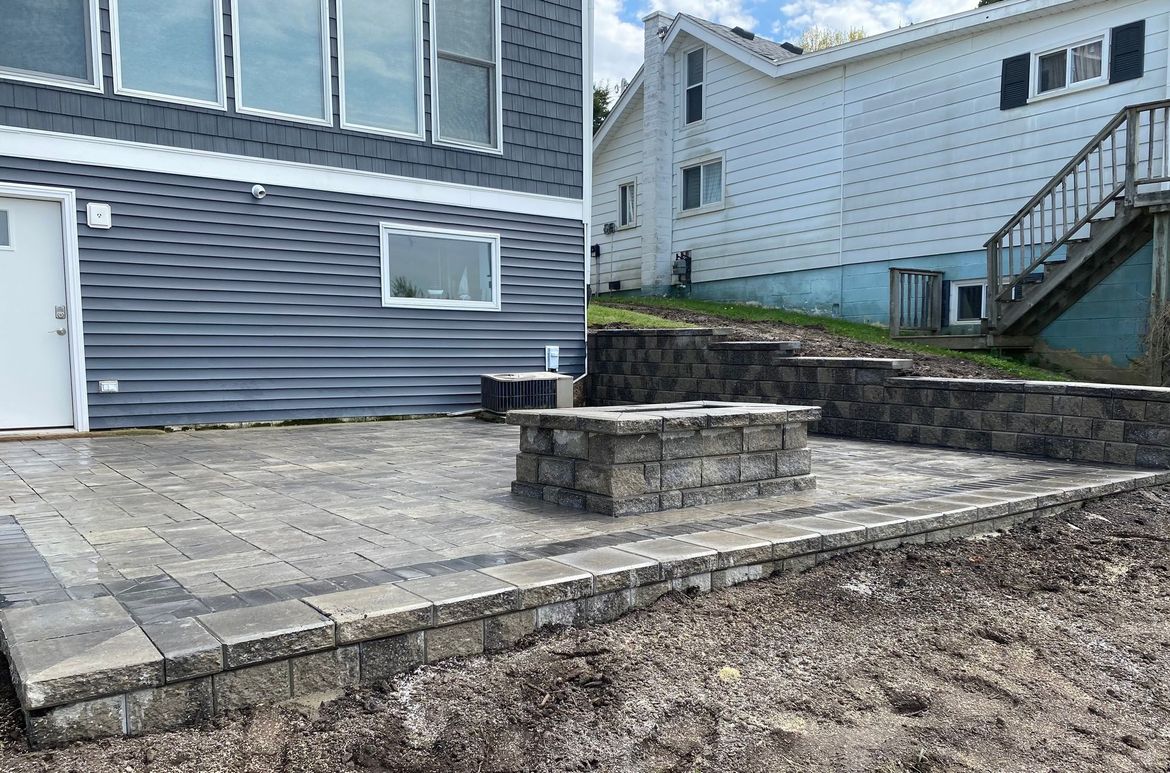 A patio with a fire pit in front of a house.