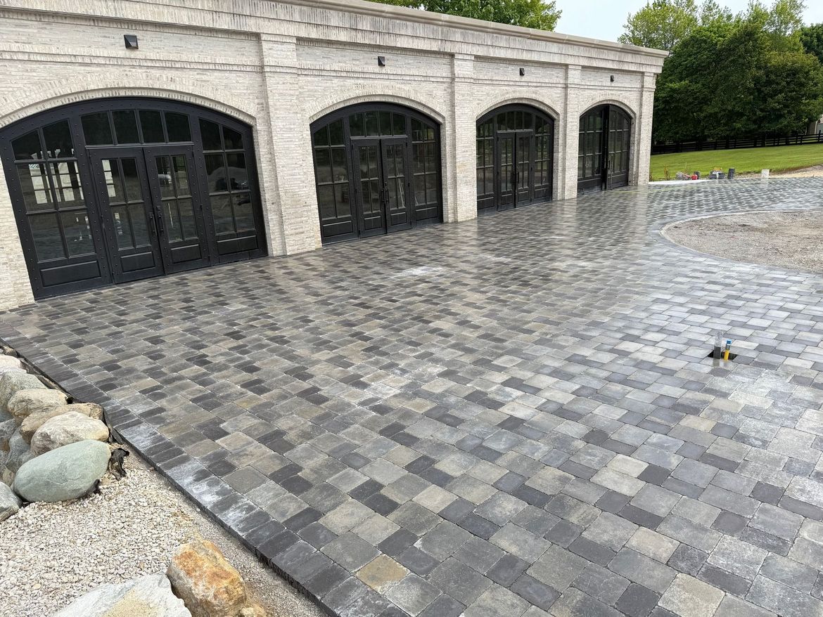 A brick driveway in front of a garage with a lot of windows.