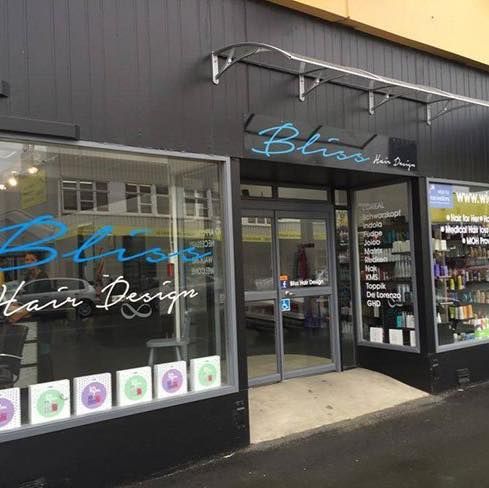 Bliss Hair Design shopfront with signage, glass doors, and display windows. Exterior shot, dark gray with a blue logo.