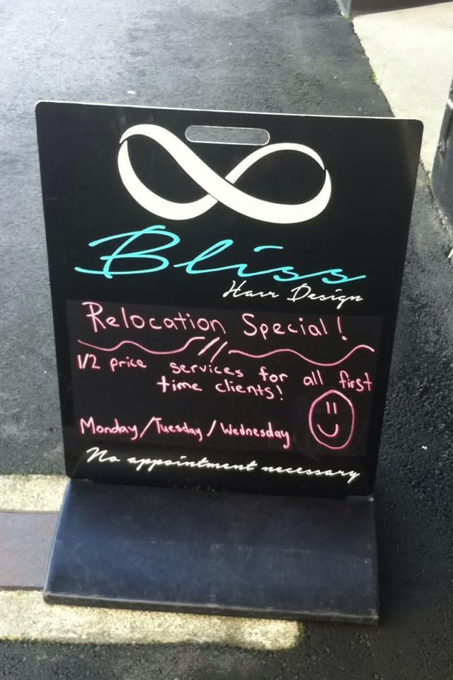 Black chalkboard sign advertising Bliss Hair Design's relocation special: 1/2 price services for new clients, Mondays-Wednesdays.