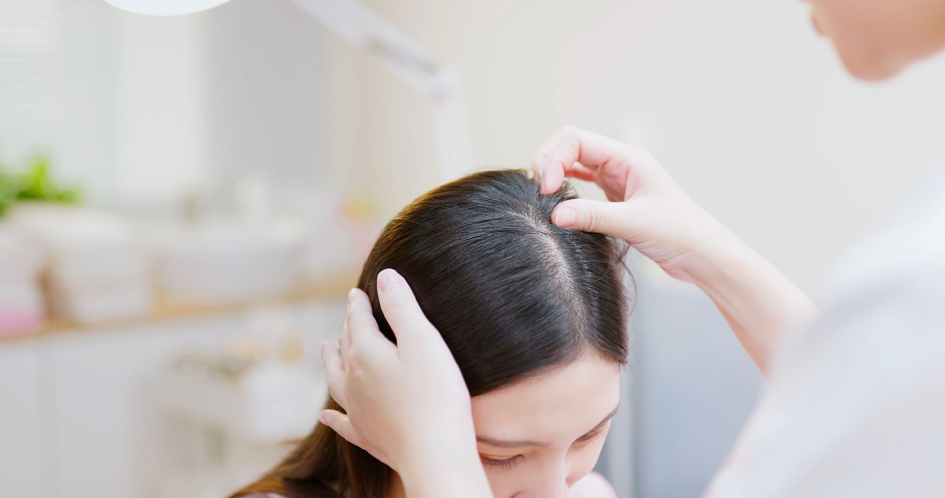 Woman with thinning hair being examined by another person.