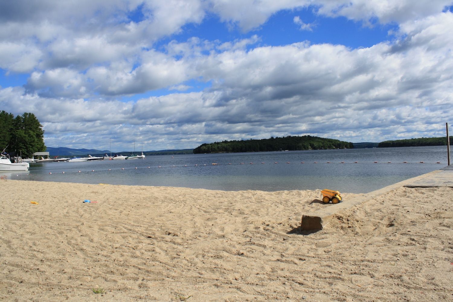 A sandy beach with a lake in the background on a cloudy day.