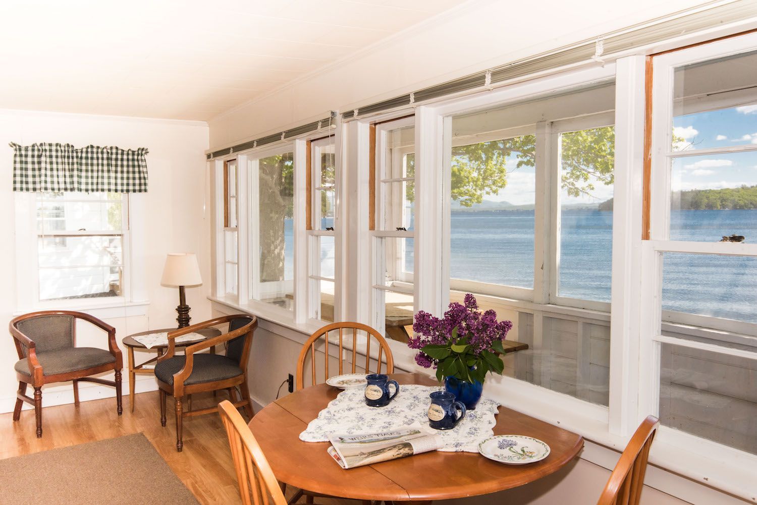 A dining room with a table and chairs and a view of a lake.