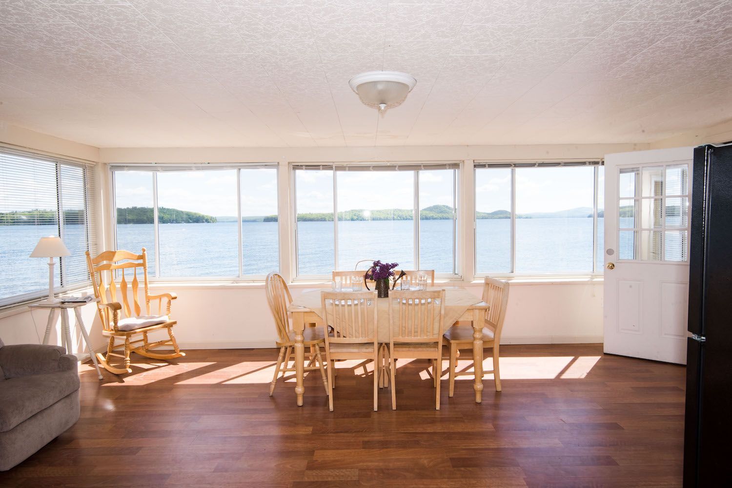 A living room with a table and chairs and a view of the water