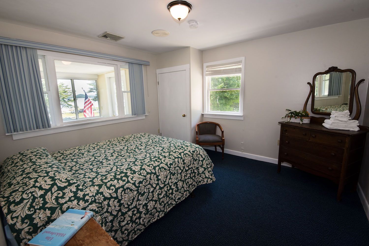 A bedroom with a bed , dresser and mirror