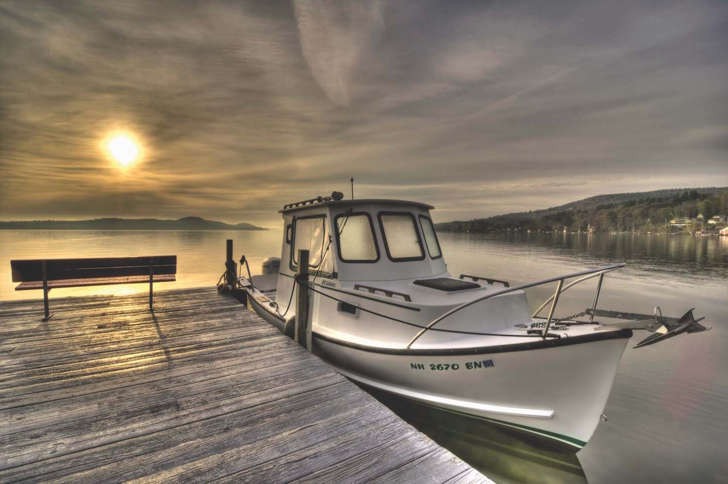 A white boat is docked at a dock on a lake