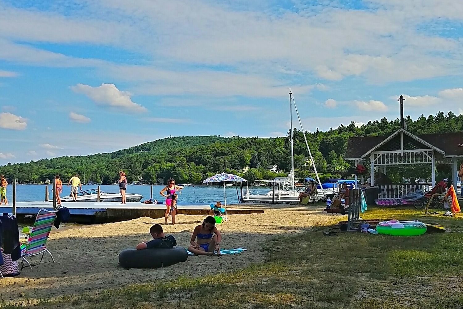 A group of people are playing on a beach near a lake.