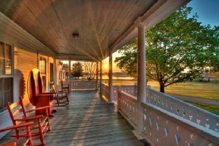 There are rocking chairs on the porch of a house.