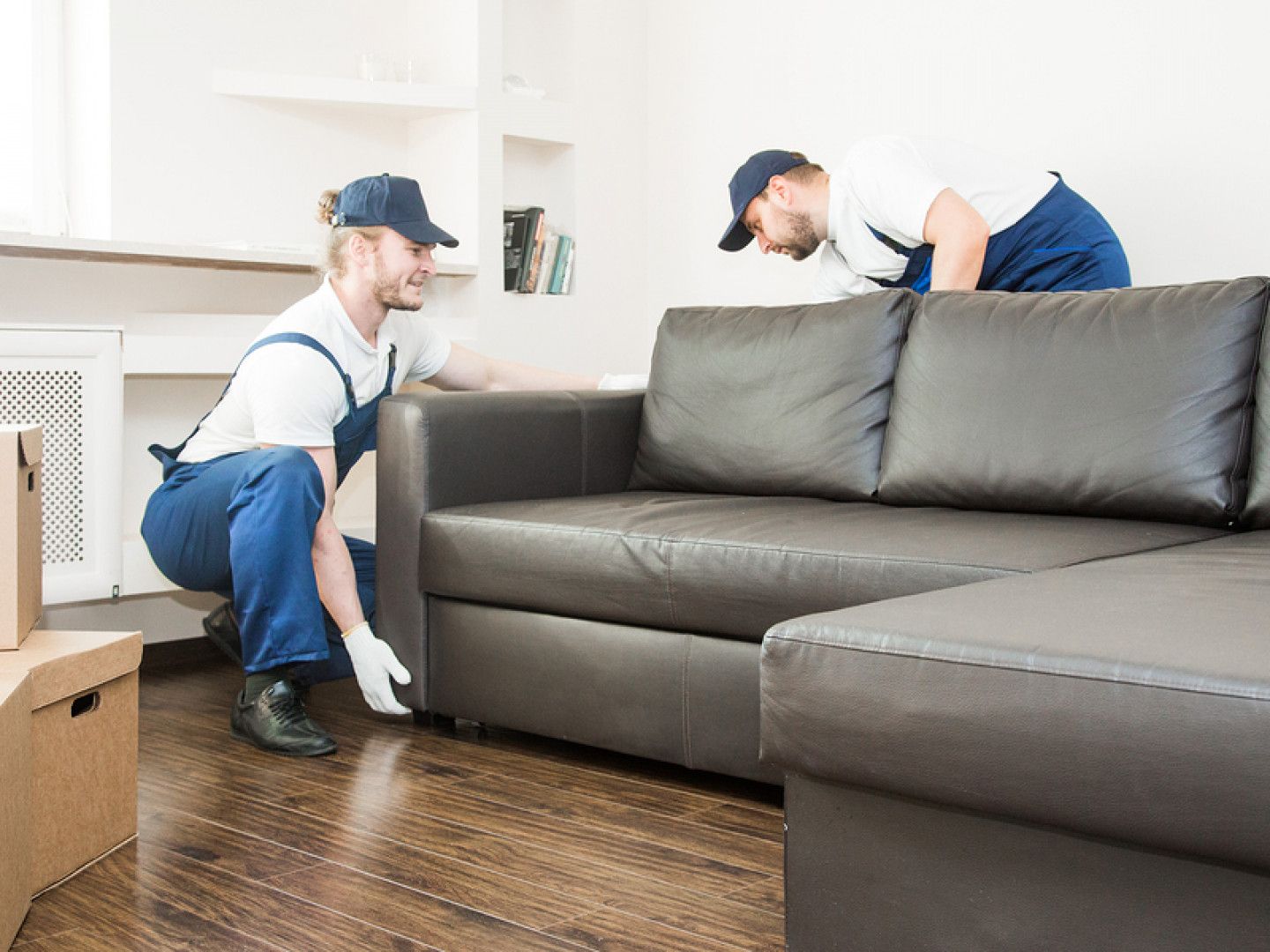 two men are moving a couch in a living room