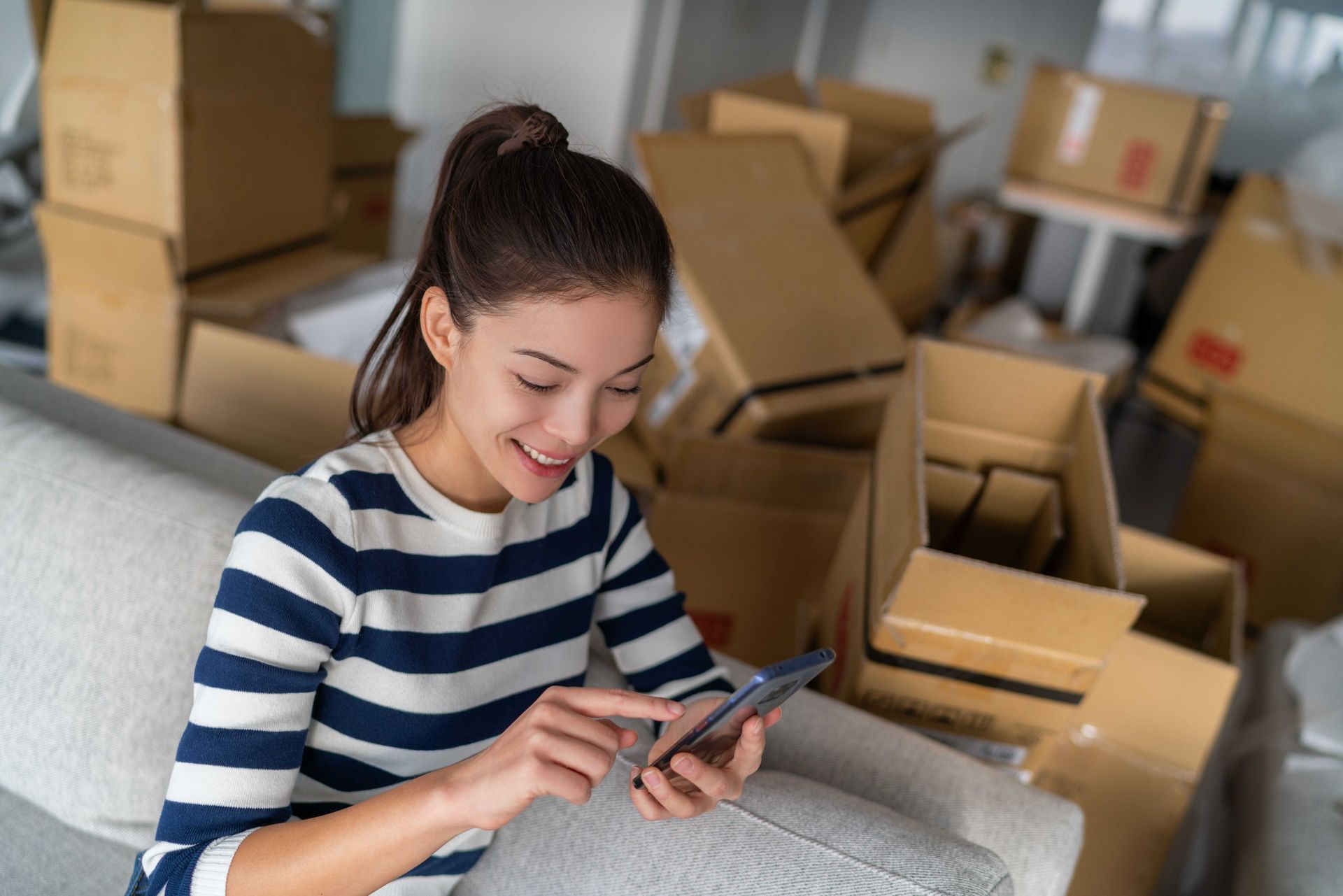 a woman is sitting on a couch using a cell phone