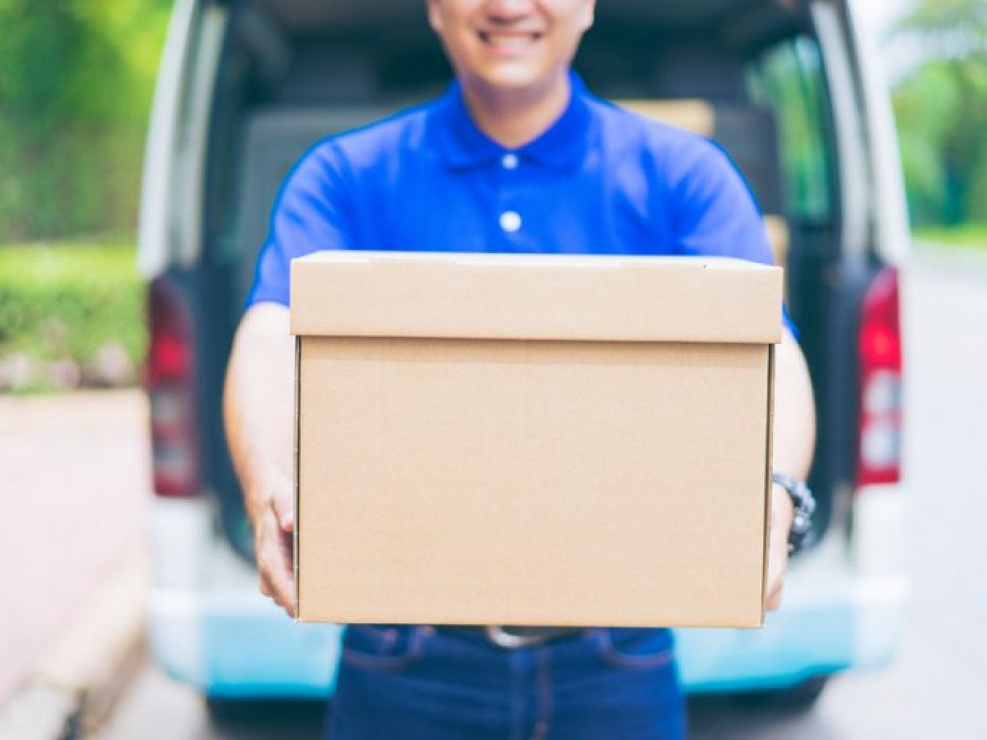 a delivery man is holding a cardboard box in front of a van