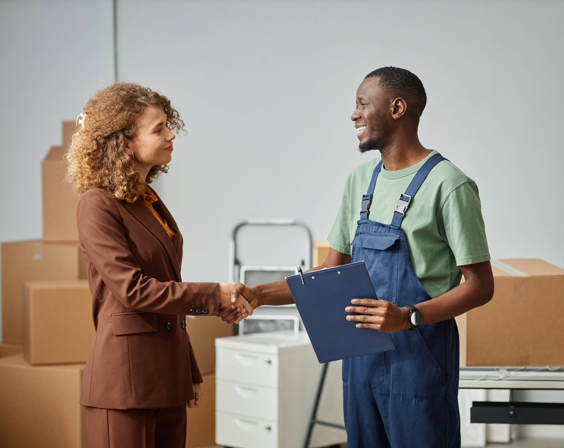 a man in overalls is shaking hands with a woman in a suit