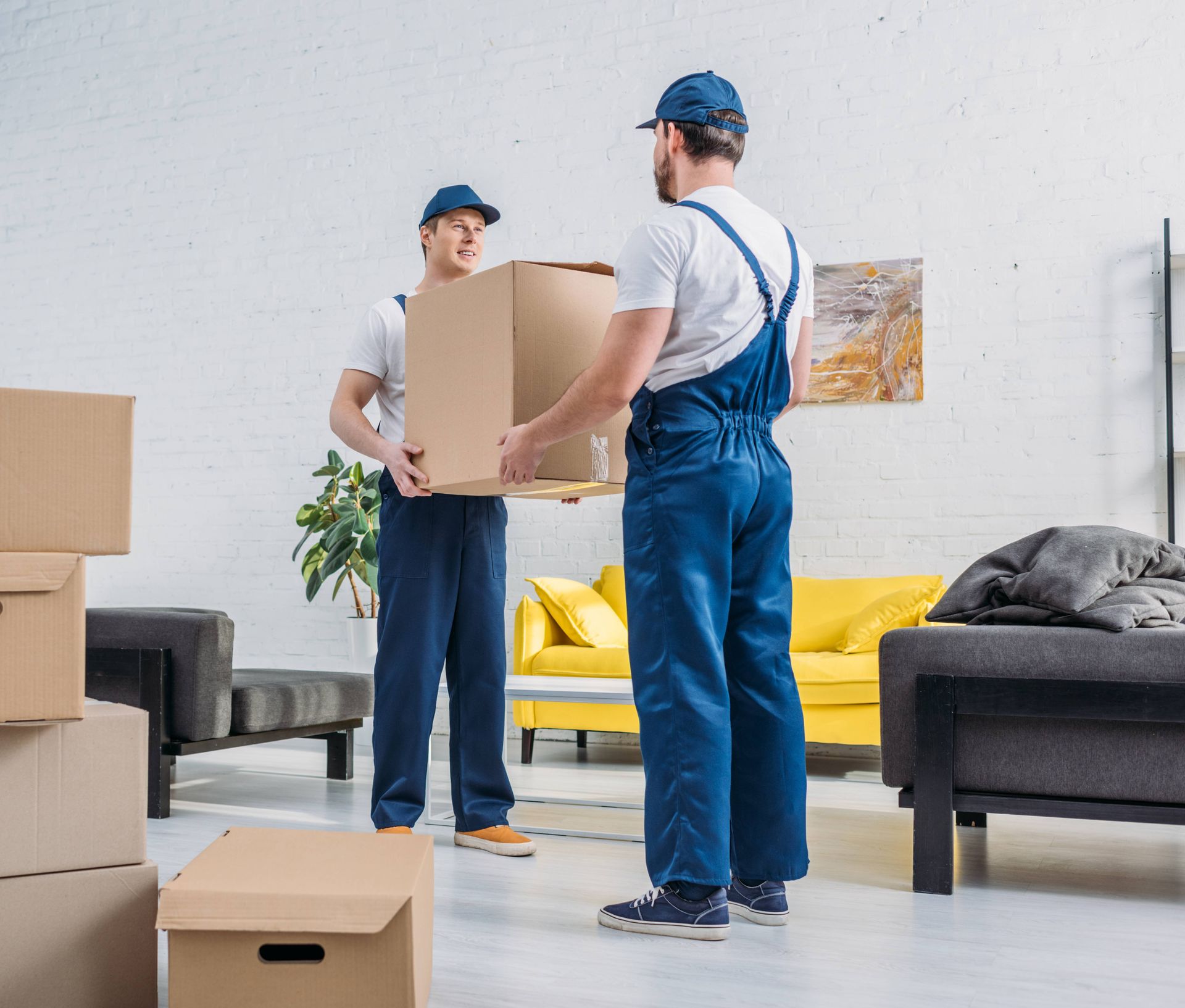 two men are moving boxes in a living room