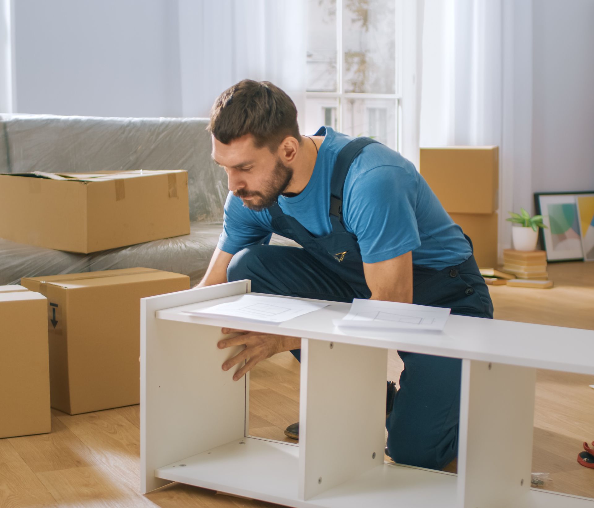 a man is kneeling down to assemble a shelf in a living room