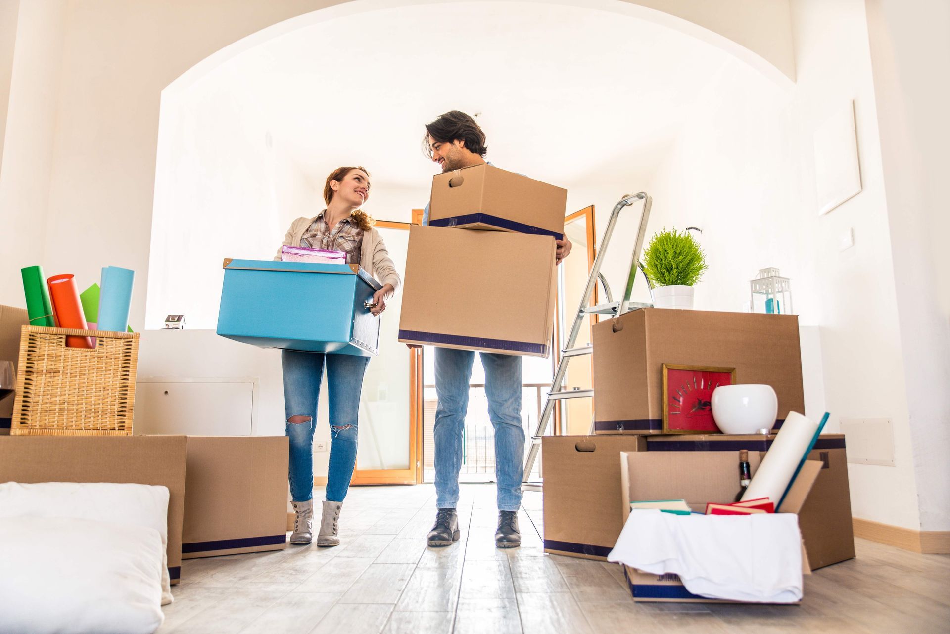 a man and a woman are carrying boxes into a new home