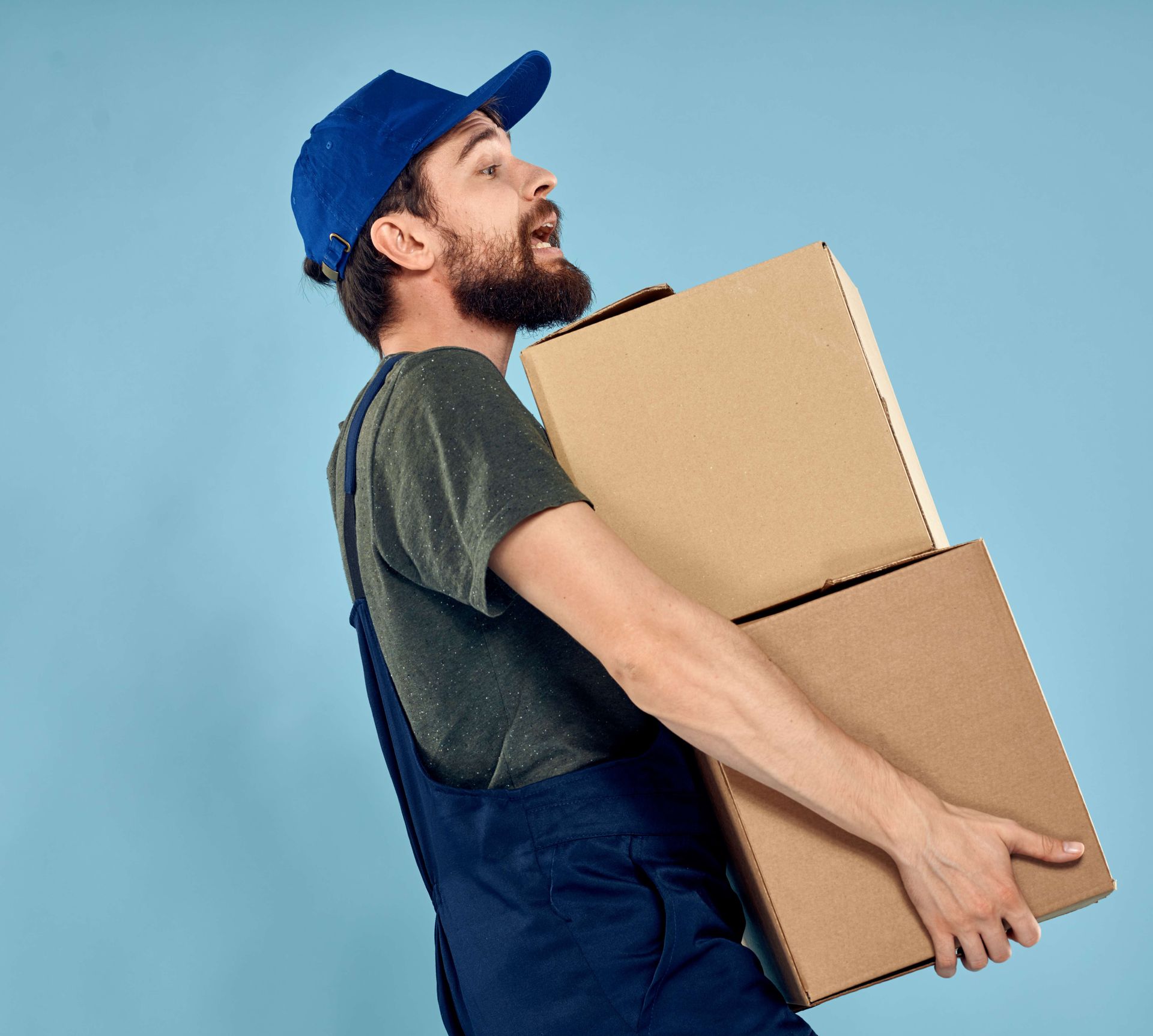 a man in a blue hat is carrying two cardboard boxes