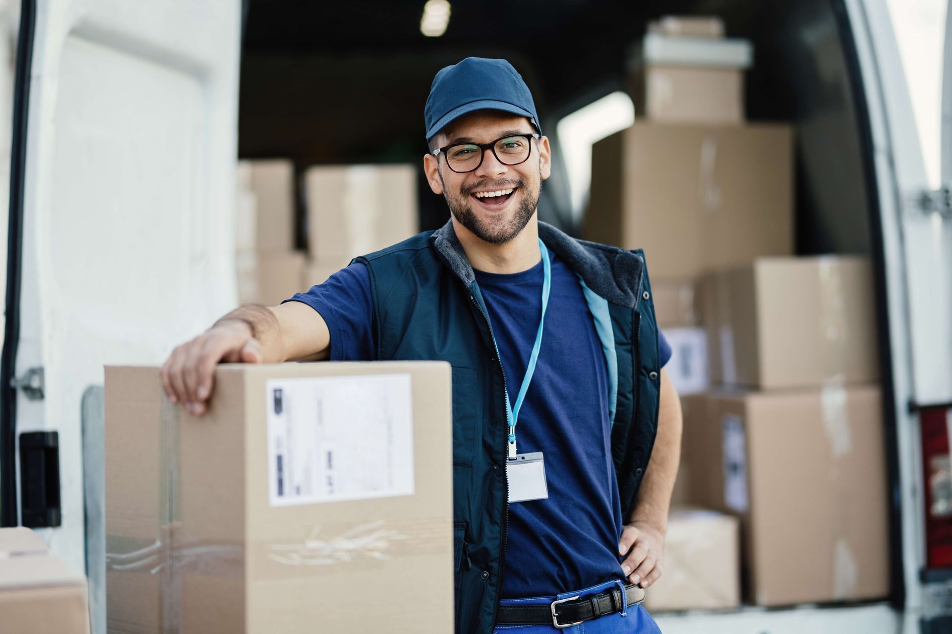 a delivery man is standing in front of a van holding a cardboard box