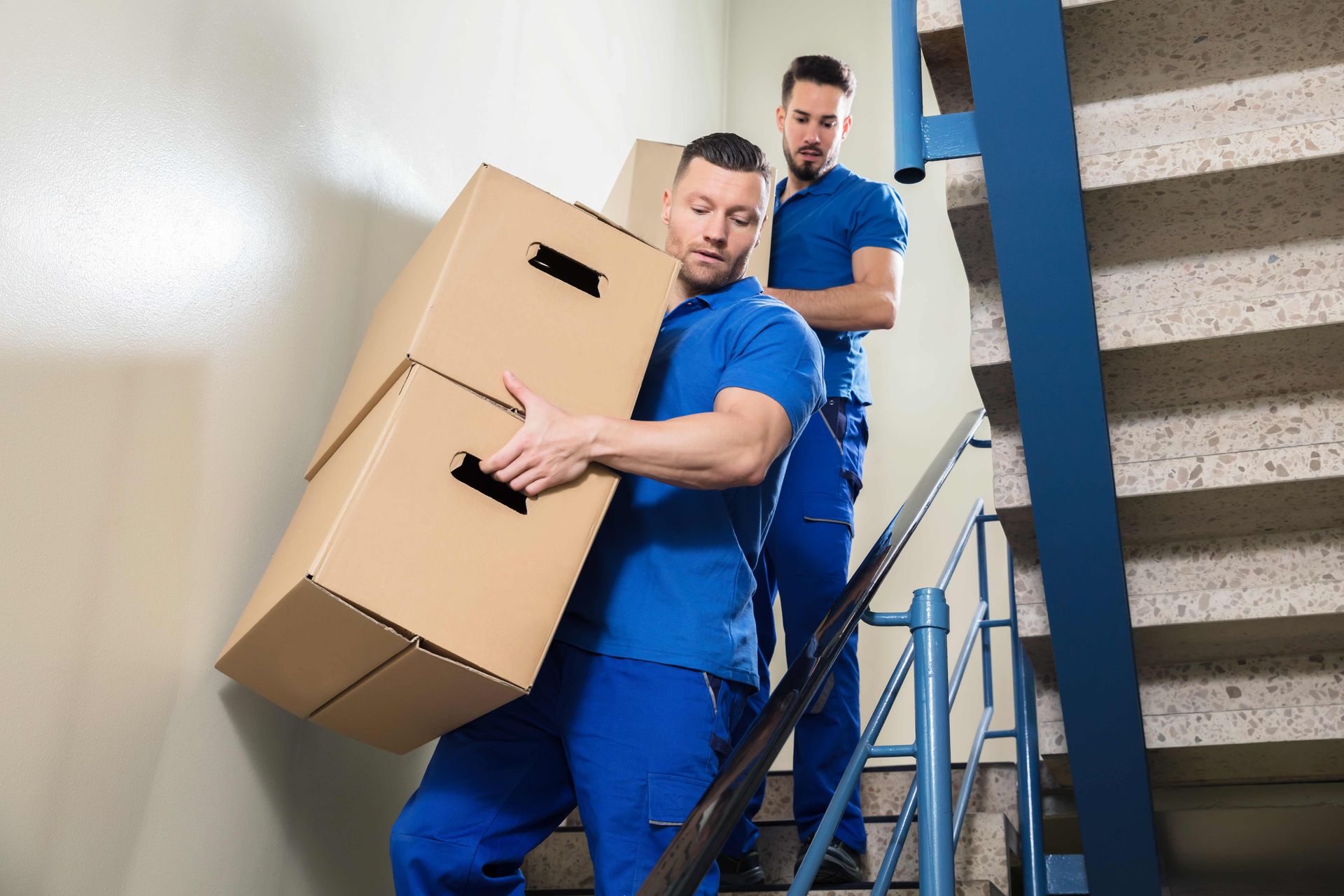 two men are carrying boxes up a set of stairs