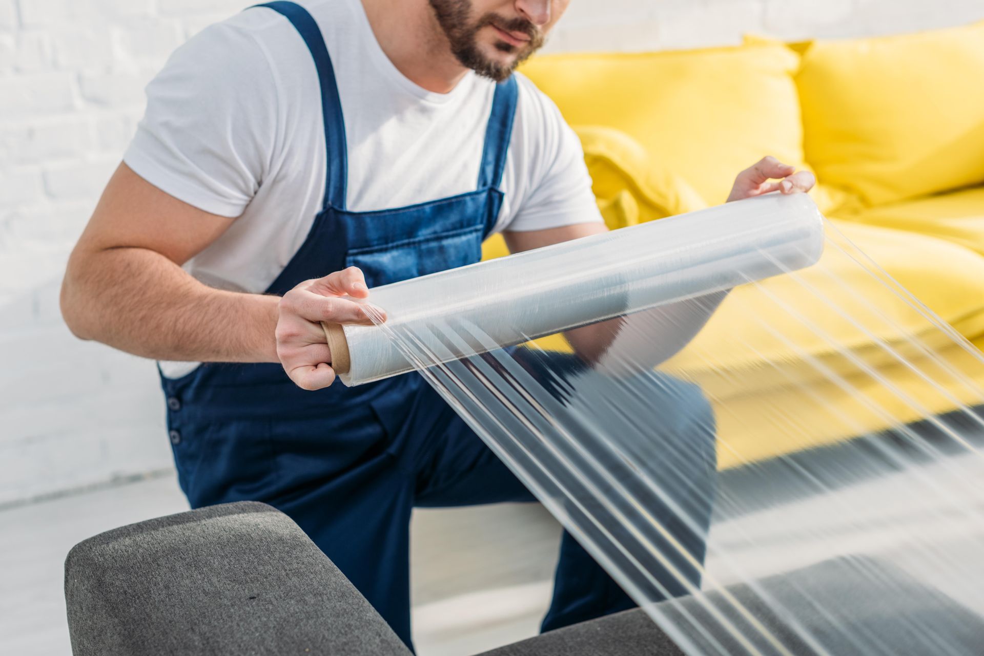 a man is wrapping a couch with plastic wrap