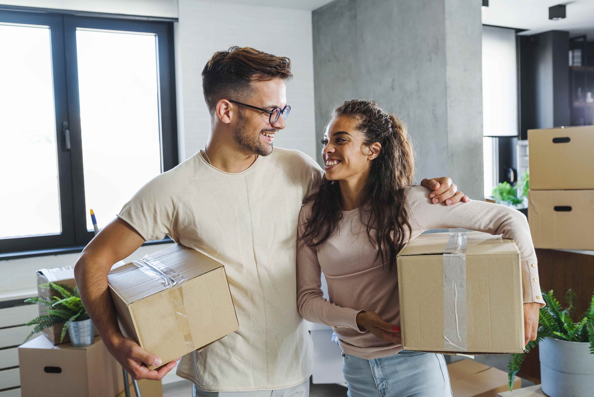 a man and a woman are holding cardboard boxes in their new home