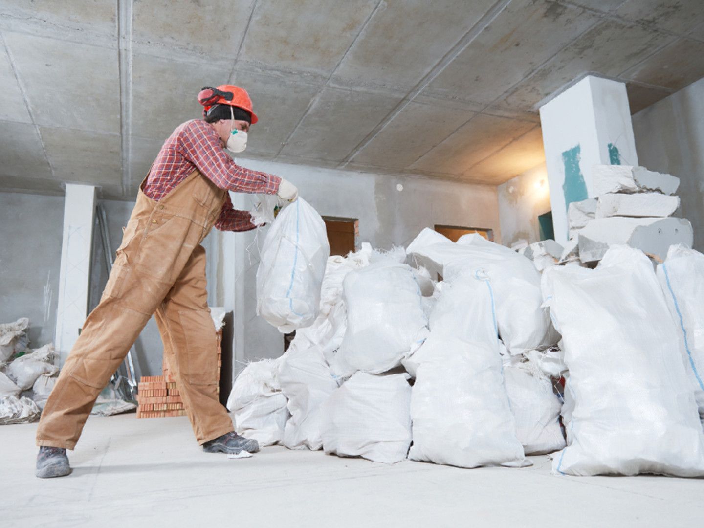 a construction worker is carrying a bag of rubble in a room