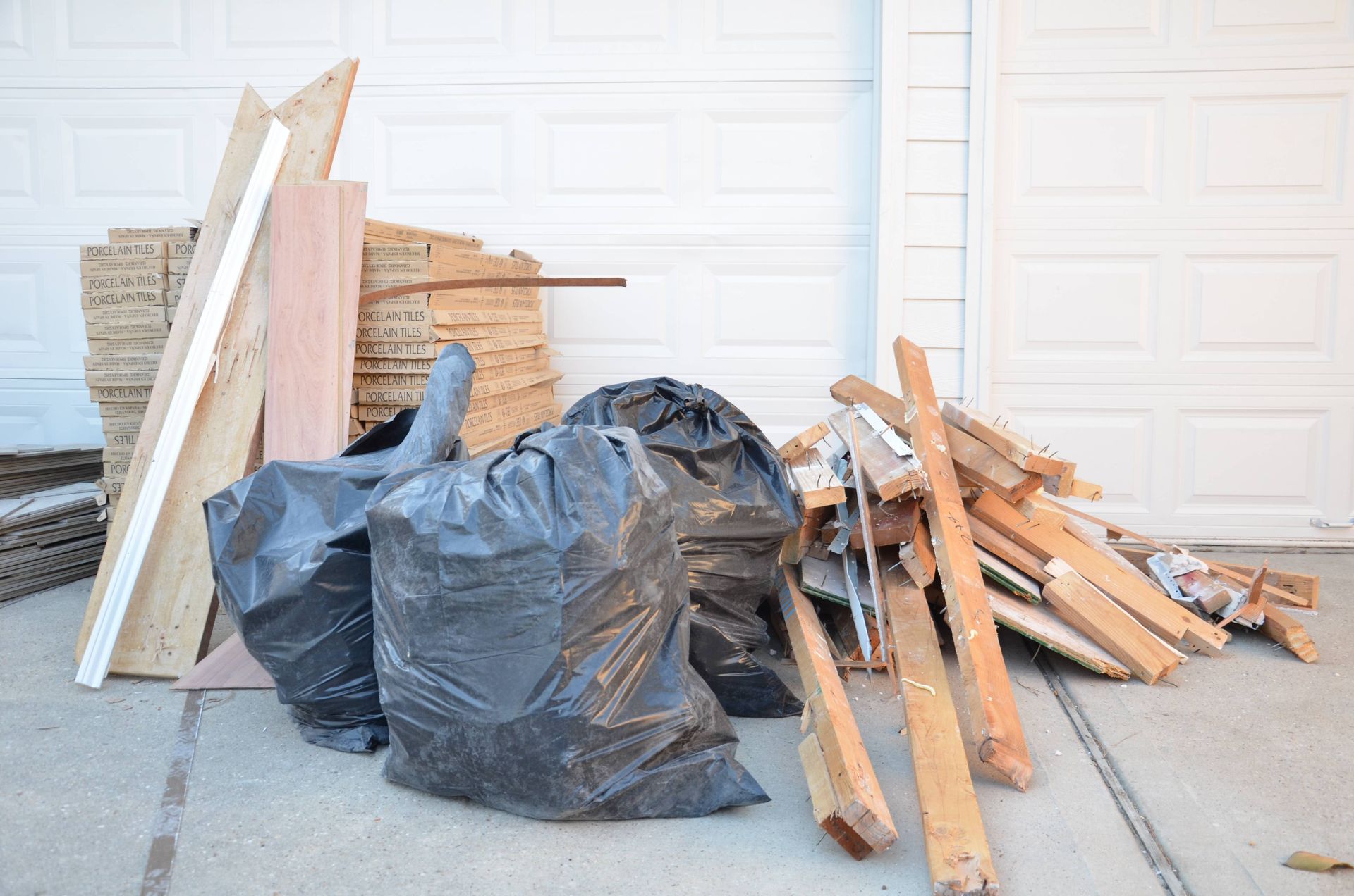 a pile of wood is sitting on the sidewalk in front of a garage