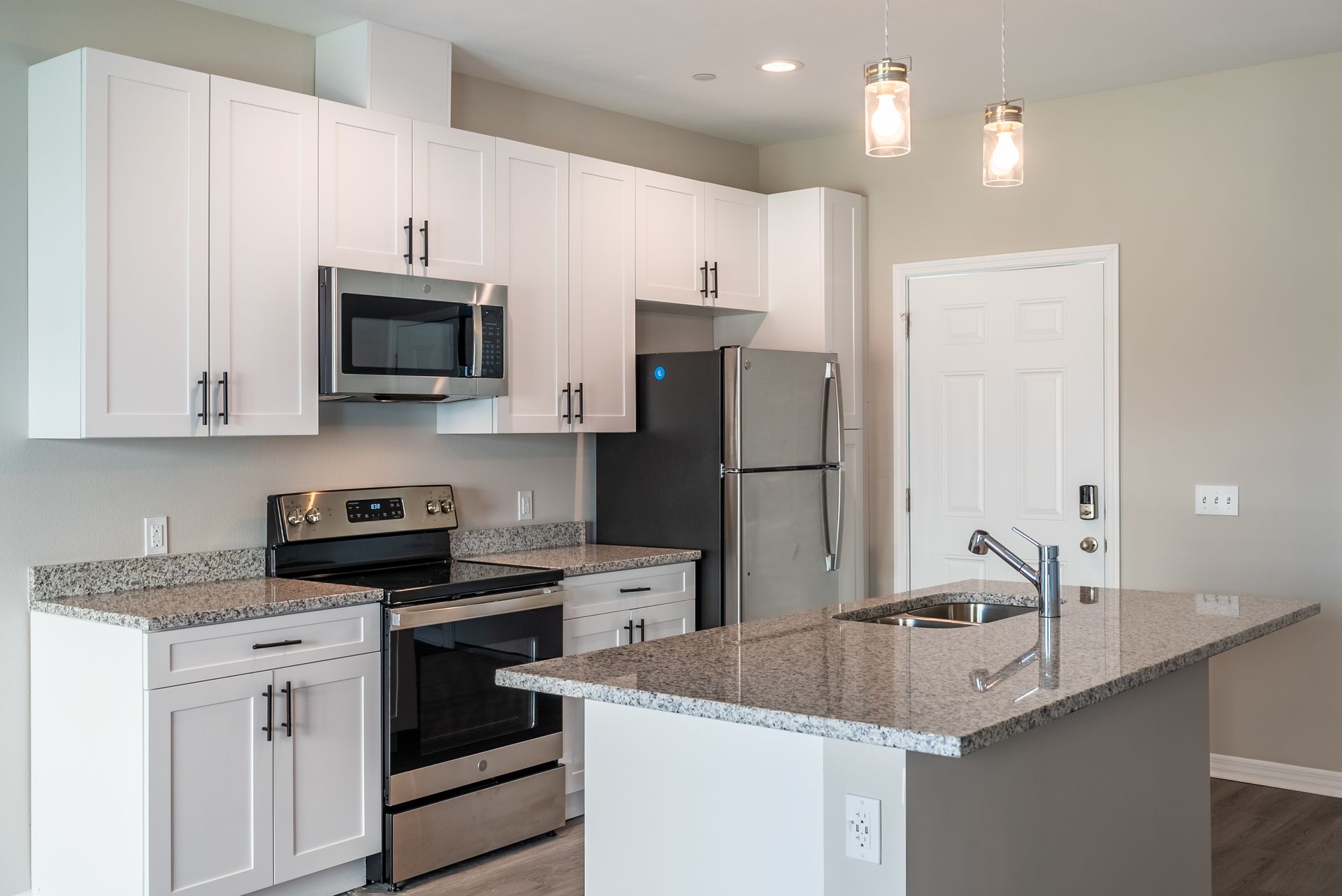 a kitchen with white cabinets , stainless steel appliances , granite counter tops and a large island at Whitney Place Apartments in Clearwater, FL.