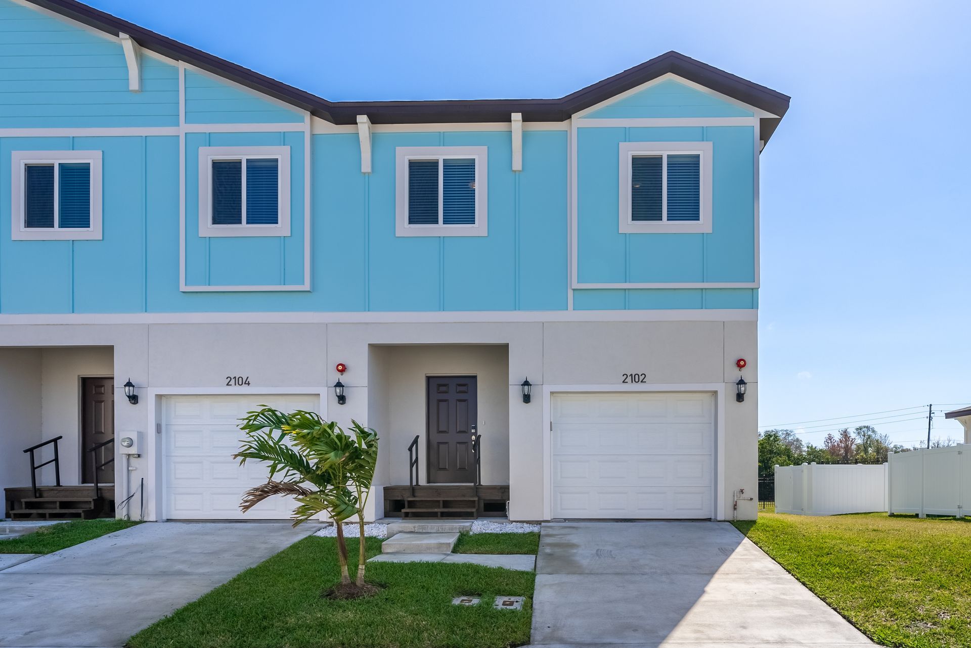 the front of a blue and white apartment with two garages at Whitney Place Apartments in Clearwater, FL.