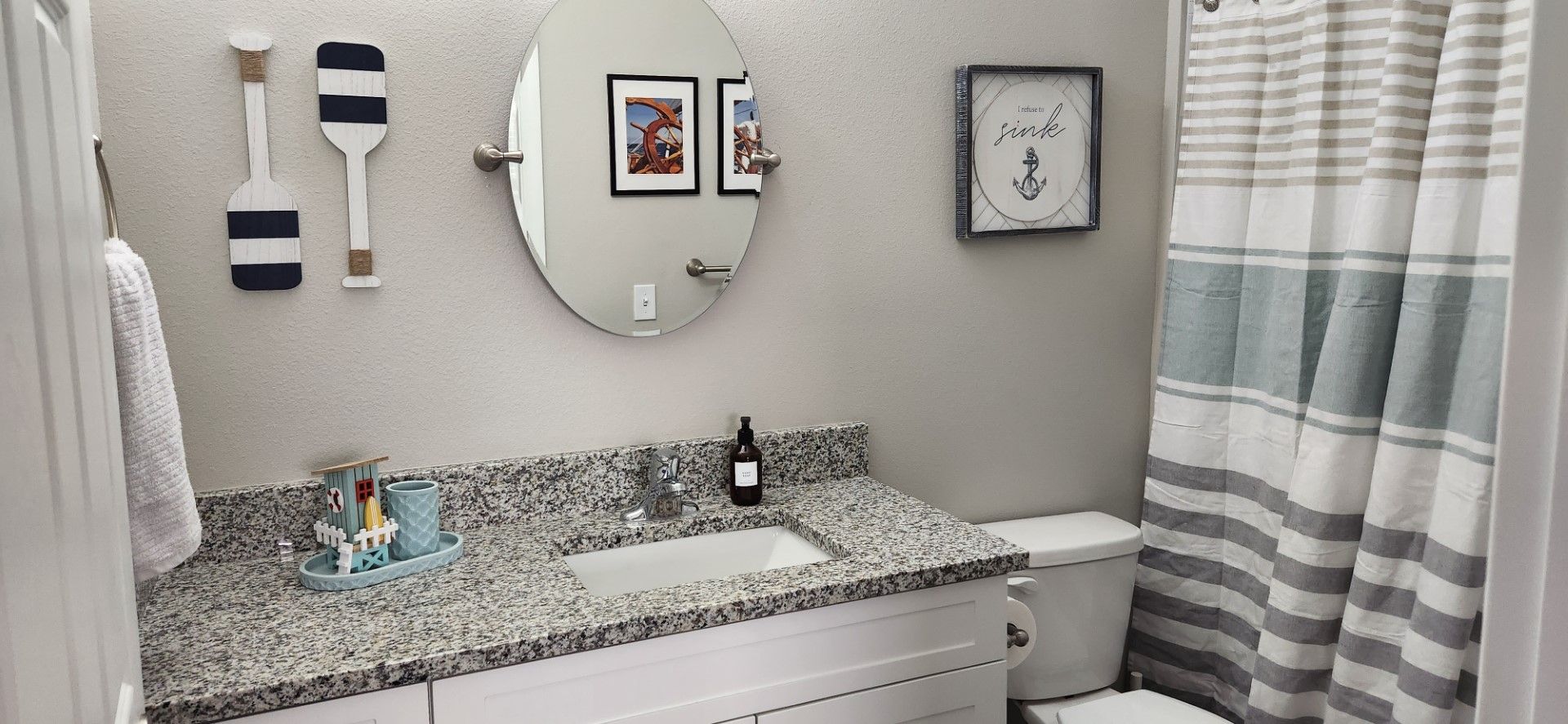 a bathroom with a sink , toilet , shower curtain and mirror at Whitney Place Apartments in Clearwater, FL.