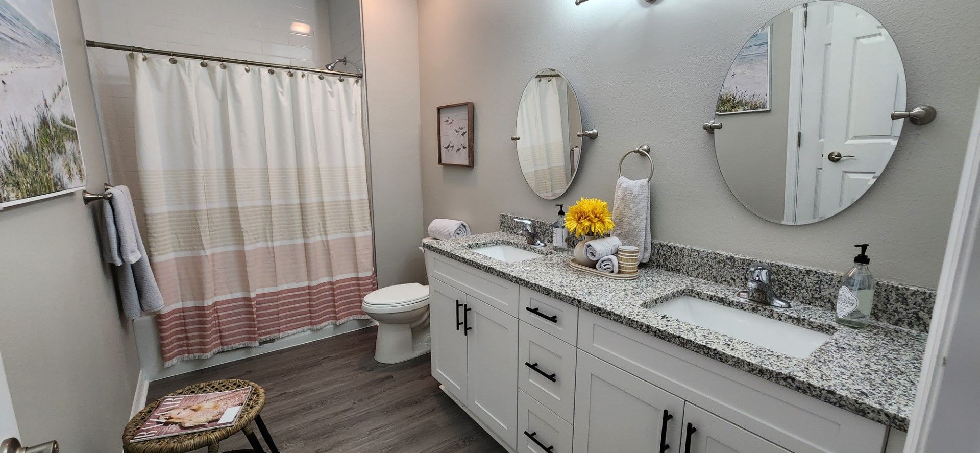 a bathroom with two sinks , a toilet , and a shower curtain at Whitney Place Apartments in Clearwater, FL.