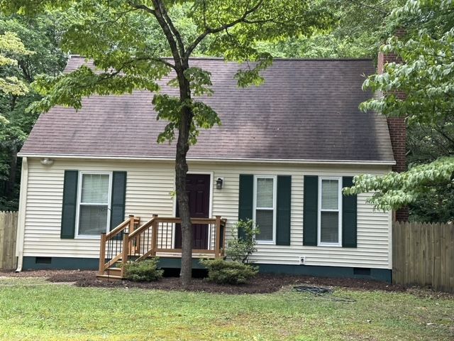 A white house with black shutters and a wooden deck