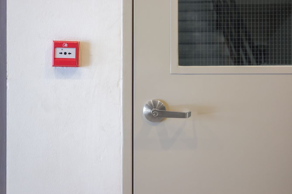 Alarm Box on a White Wall Next to a Closed Door With Window — Local Glassmaster in Huskisson, NSW